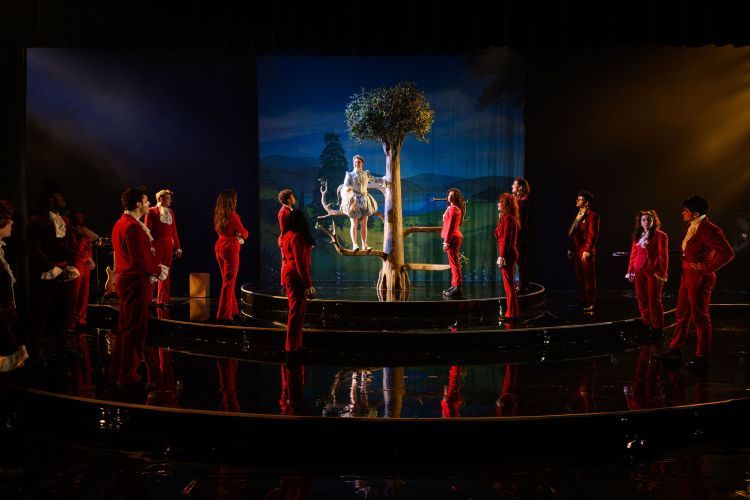 Scene from Orlando - actors surrounding tree in red suits